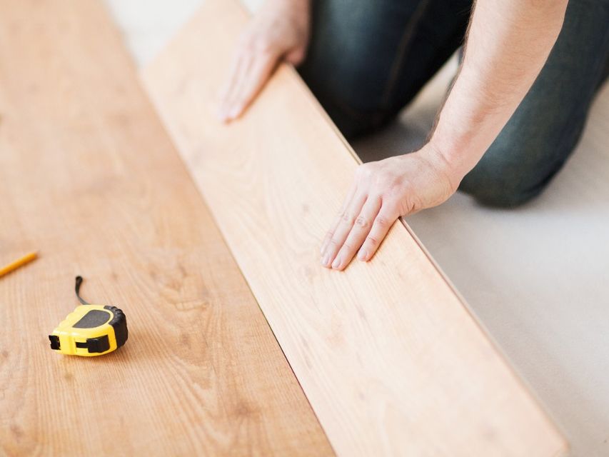 Reparación, construcción y concepto de hogar - cerca de las manos masculinas intalling pisos de madera